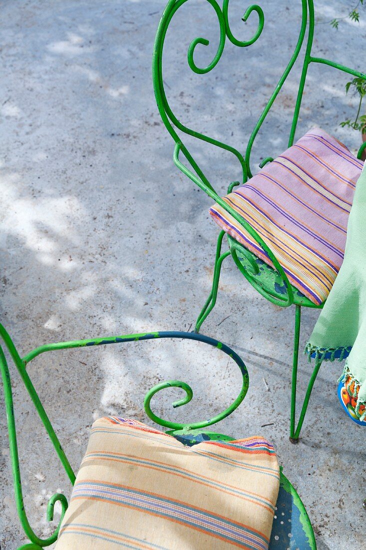 Green, vintage-style metal chairs with striped seat cushions