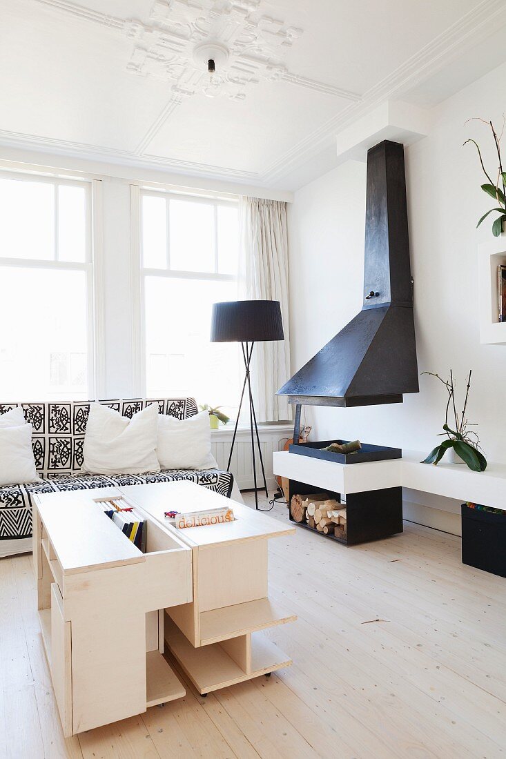 Pale-wood, custom coffee table and open fireplace with hood in living room