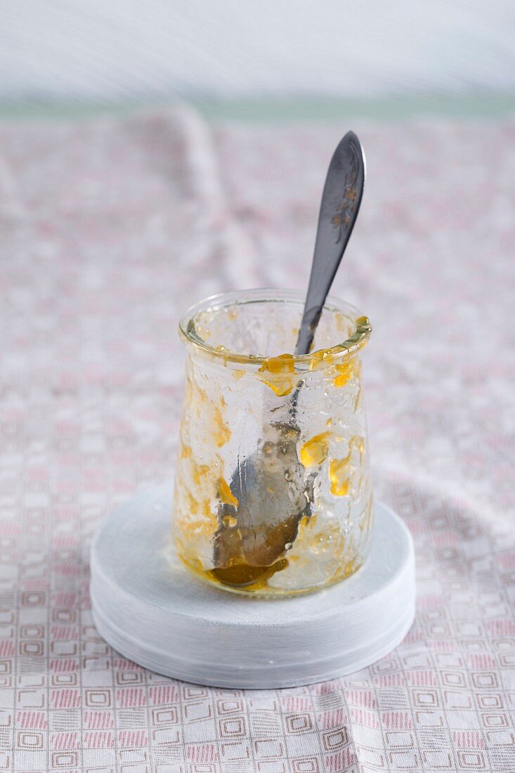 Leeres Marmeladenglas mit Resten von Aprikosenmarmelade