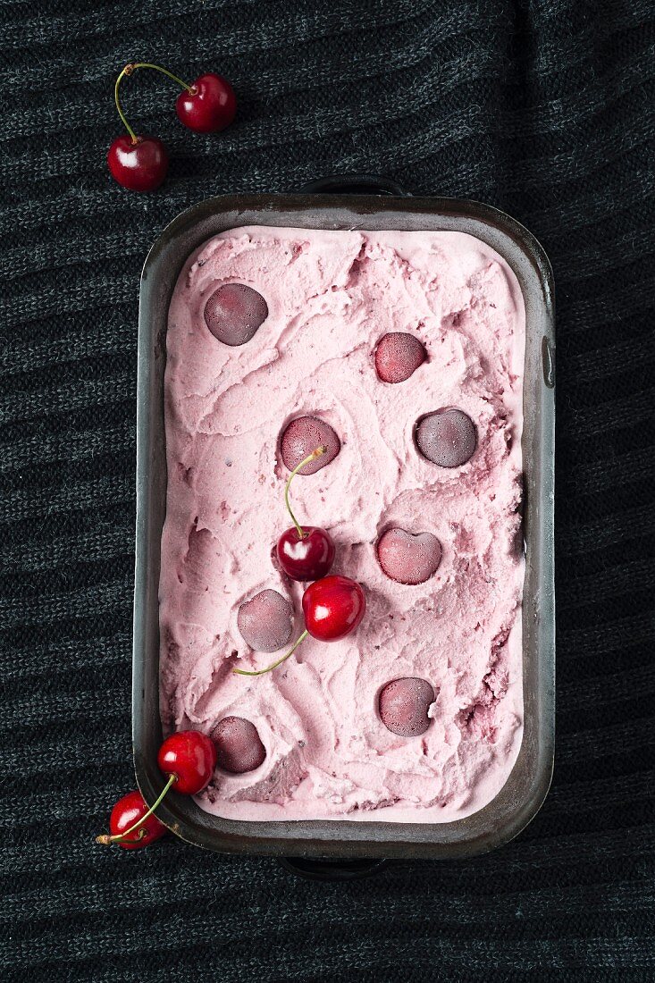 Homemade cherry ice cream in an ice cream container