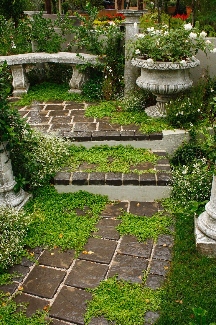 Garden steps leading to antique stone bench, planted urn & low columns