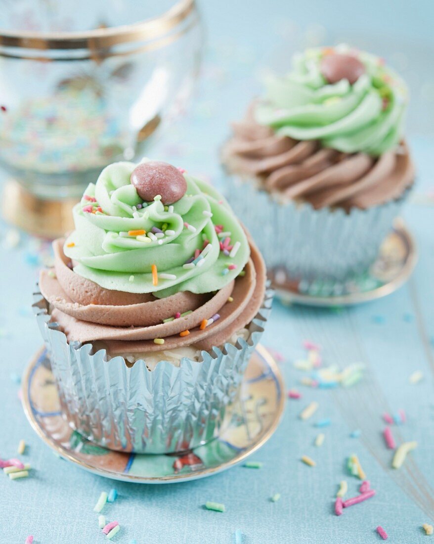 Cupcakes mit Schokoladen- und Limettencreme dekoriert mit Schokolinsen und Zuckerstreuseln