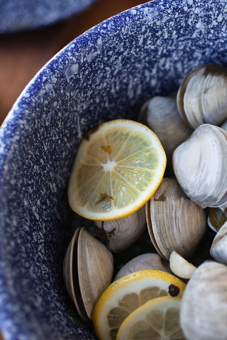 Steamed clams in a white wine broth with garlic and herbs in an enamel pot