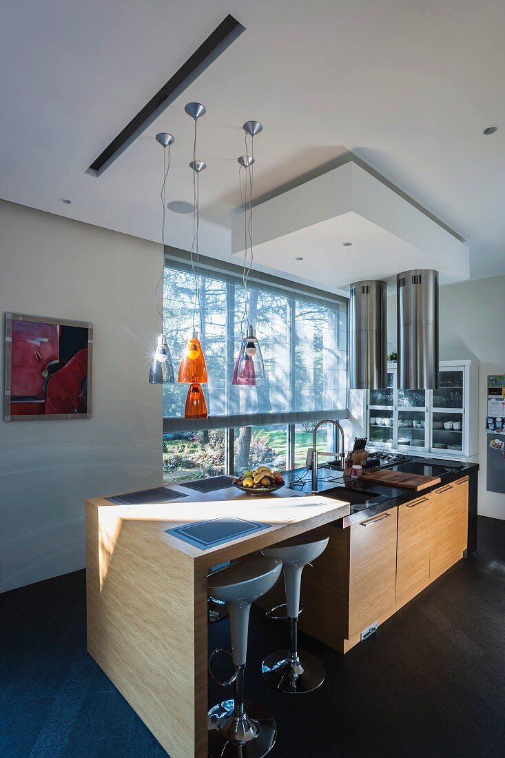 Designer breakfast bar with white bar stools and island counter in front of glass wall