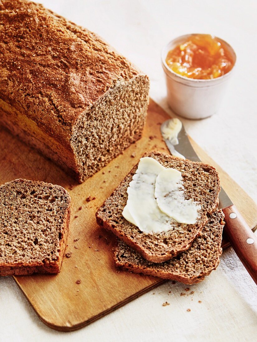 A loaf of wholemeal bread with butter and marmalade