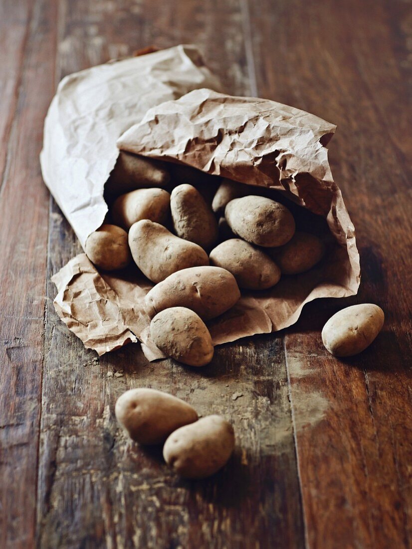 Kartoffeln im Papiersack auf Holzuntergrund