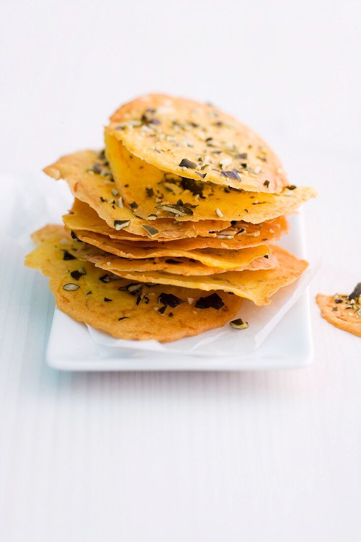 A stack of pumpkin crisps with chopped pumpkin seeds