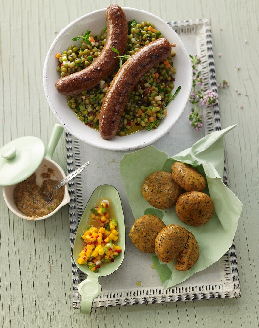 Linsen-Petersilien-Falafel mit rohem Mangochutney, gebratene Merguez mit Bärlauchsenf und Mungobohnensalat