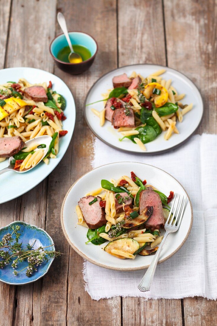 Penne pasta salad with roast beef, courgette, dried tomatoes and spinach