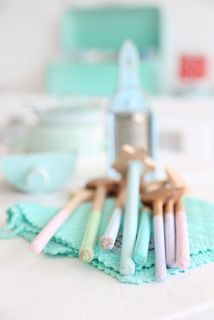 Vintage wooden spoons in pastel shades on turquoise, lacy doily