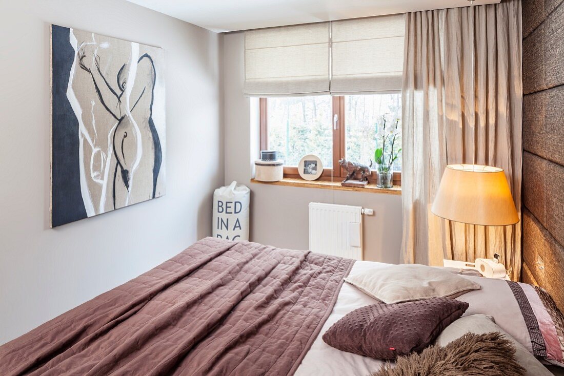 Modernes Bild und stoffbezogene Rückwand in Schlafzimmer; Überwurf und Dekokissen in Brauntönen