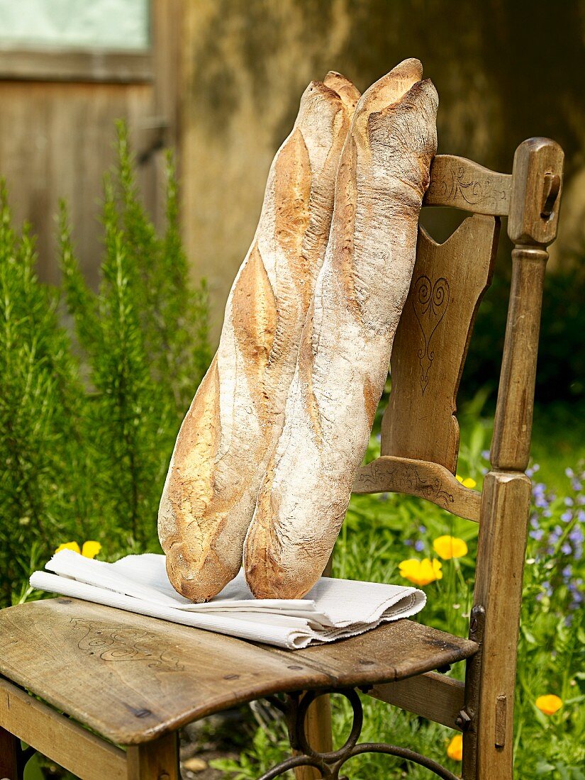 Two Milan baguettes on a wooden chair in a garden
