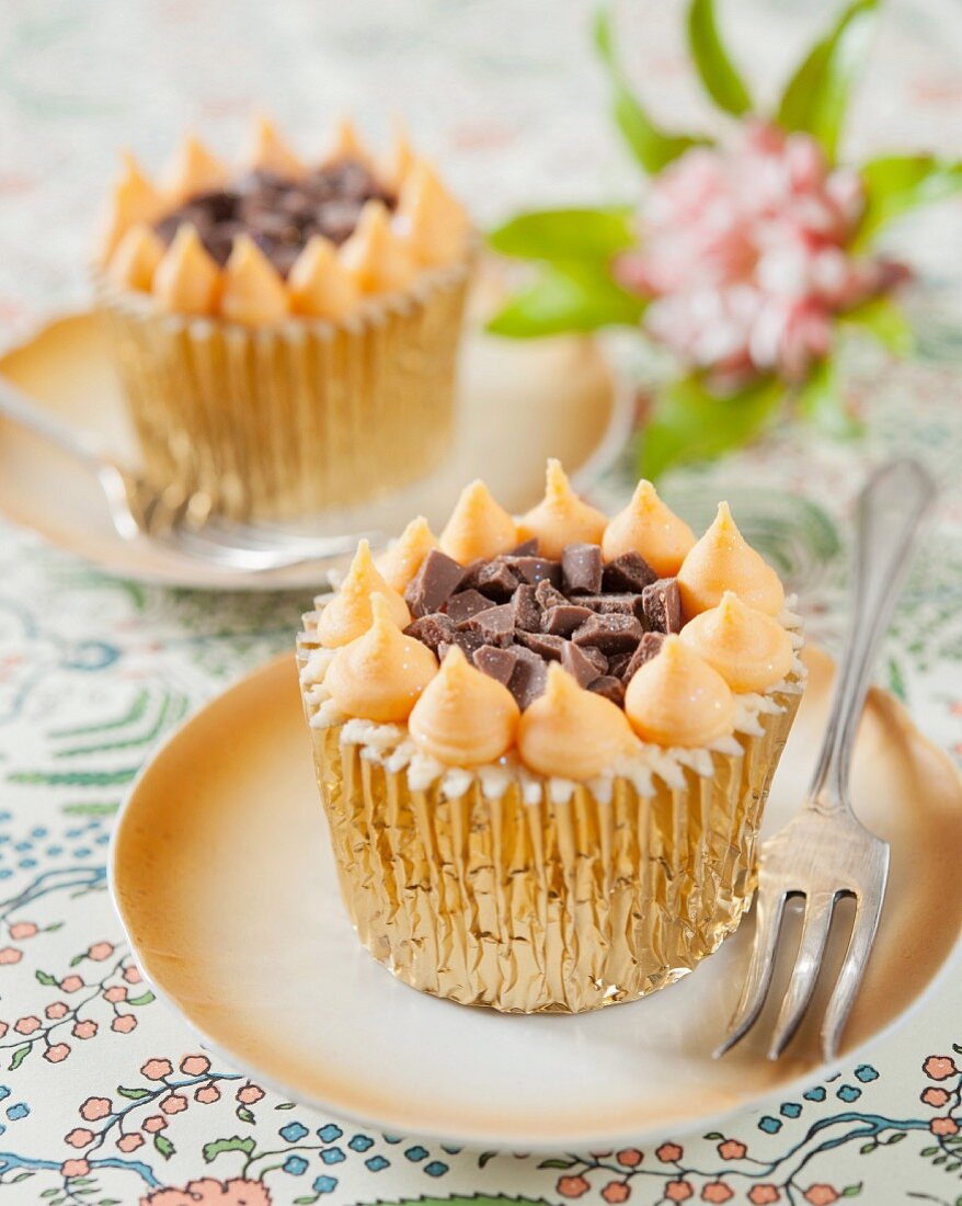 A cupcake with orange cream and chocolate chunks