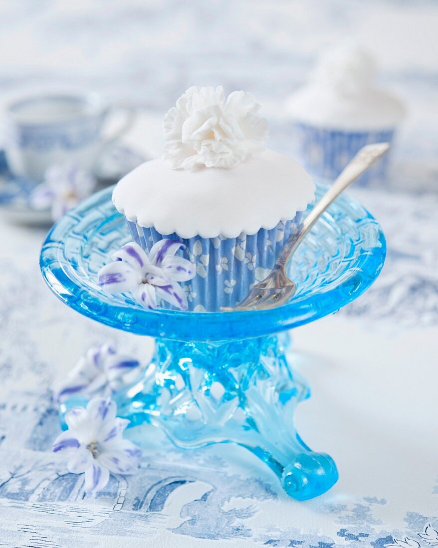 A white cupcake decorated with a white fondant flower