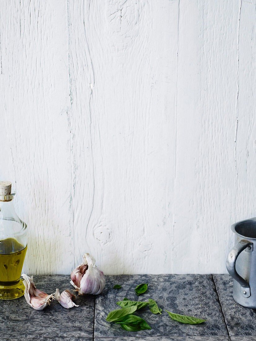 Olivenöl, Knolauch und Basilikum auf gefliester Arbeitsplatte