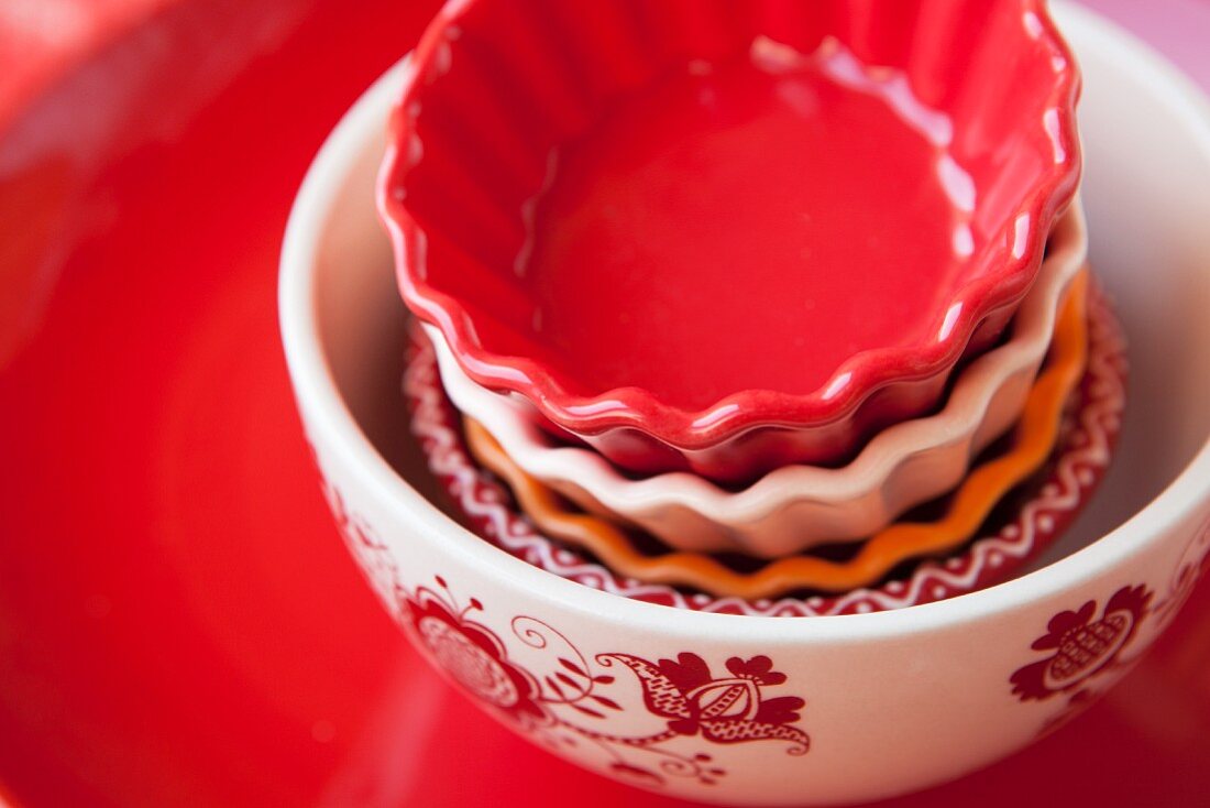 Various porcelain dishes stacked in a bowl with an ornamental pattern