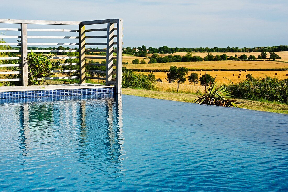Infinity Pool, im Hintergrund Holzgitter Wand auf Terrasse, vor mediterraner Landschaft