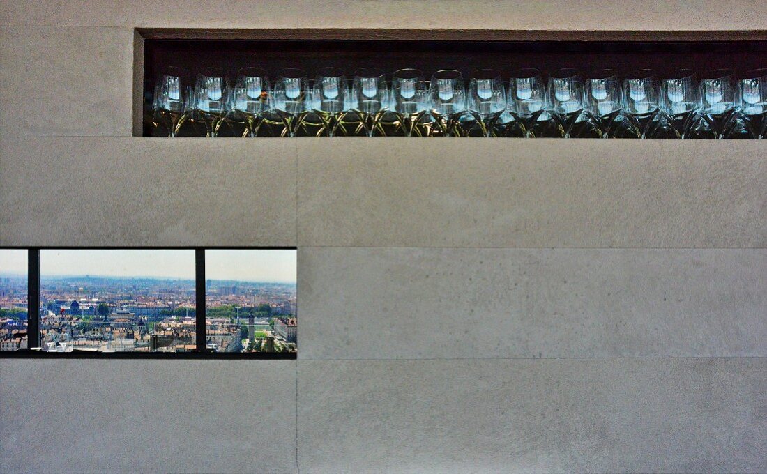 Glasses in stone-tiled niche above ribbon window with view across city