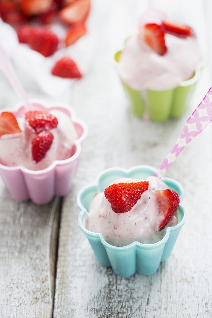 Erdbeer-Frozen-Joghurt in bunten Schälchen, bunter Löffel
