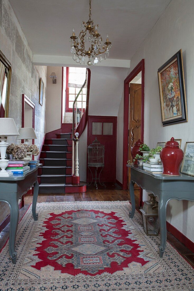 Console tables in foyer of 18th-century, French country house in shades of red and grey