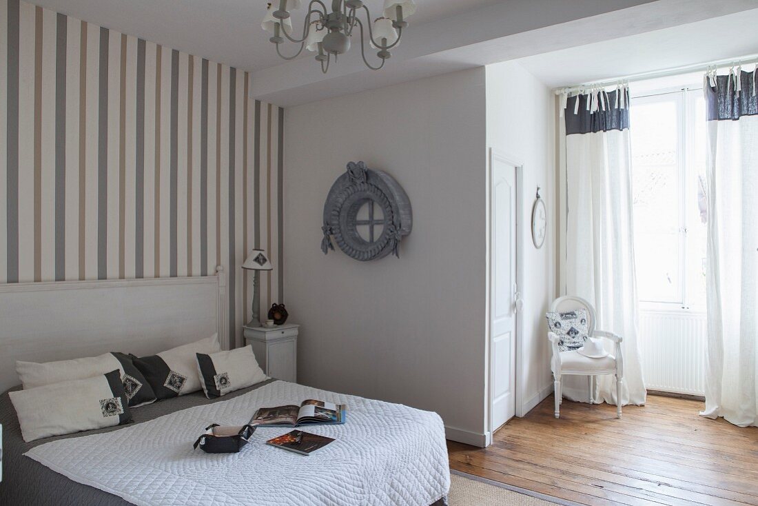 French-style, grey and white bedroom with striped wallpaper and Baroque chair