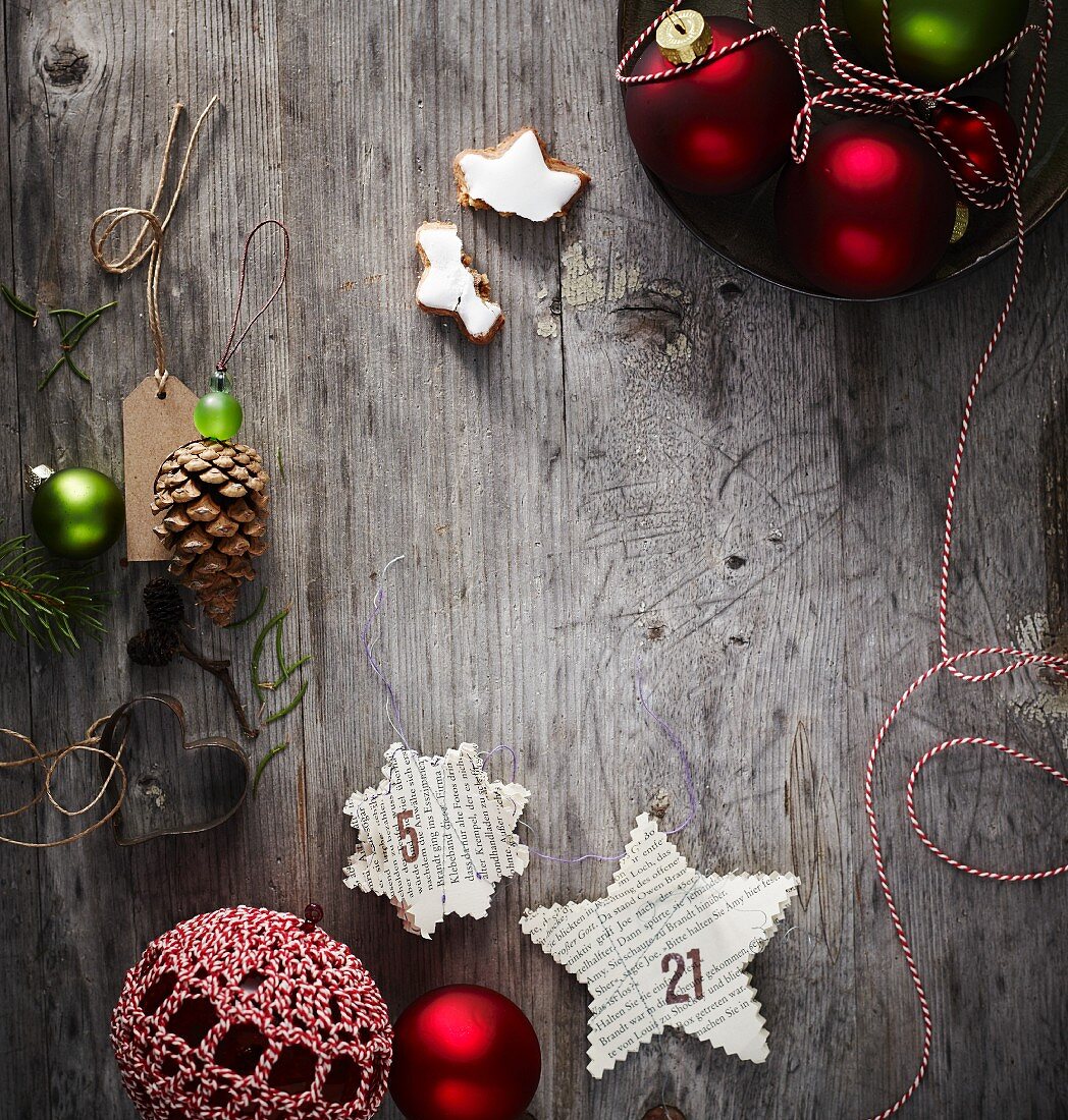 Stars cut out of book pages and other Christmas decorations on weathered wooden surface