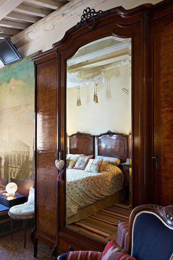 Antique wardrobe with mirrored door in traditional bedroom