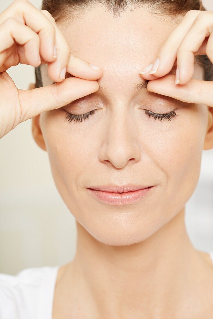 A brunette woman having an eye massage