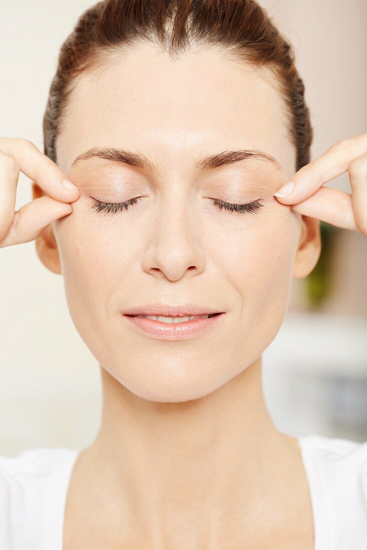 A brunette woman having an eye massage