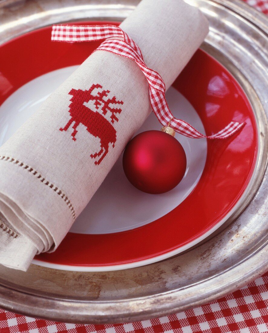 Red and white gingham ribbon, bauble and linen napkin embroidered with stag motif