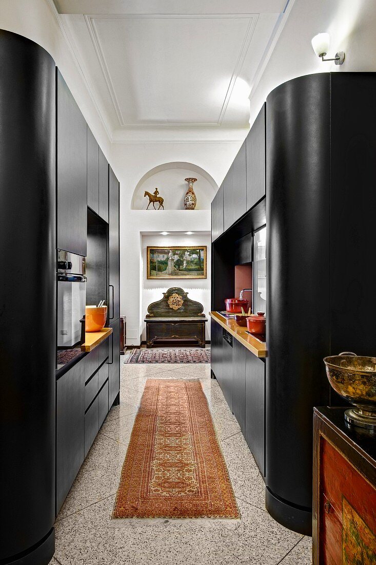 Modern, black cupboard installations with rounded edges in open-plan kitchen in traditional interior