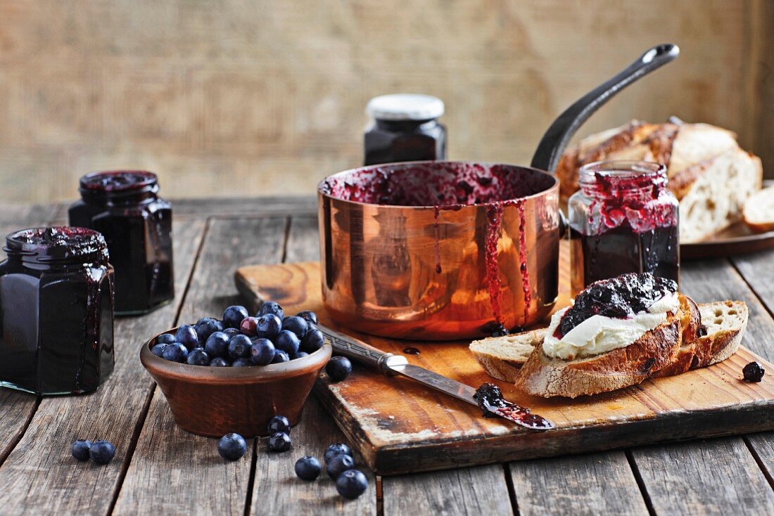 Homemade blueberry jam in a copper pan, glasses and on bread