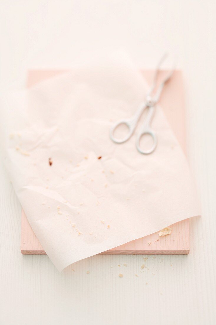 Macaroon crumbs on a white paper with a pair of kitchen tongs