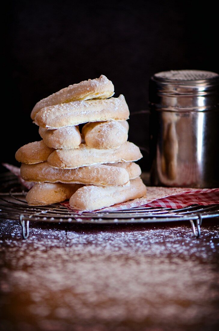 A stack of homemade sponge fingers on a cooling rack