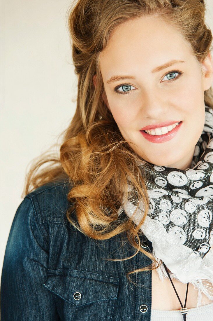 A young woman wearing a denim shirt and a scarf