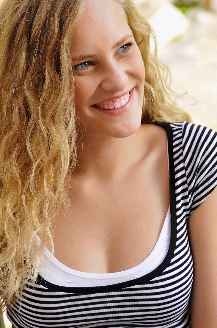 A smiling young woman wearing a stripped shirt with a wide neckline