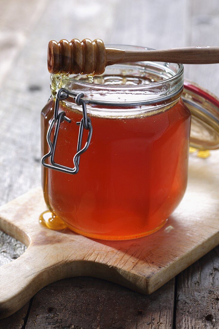 Honig im Glas mit tropfendem Honiglöffel