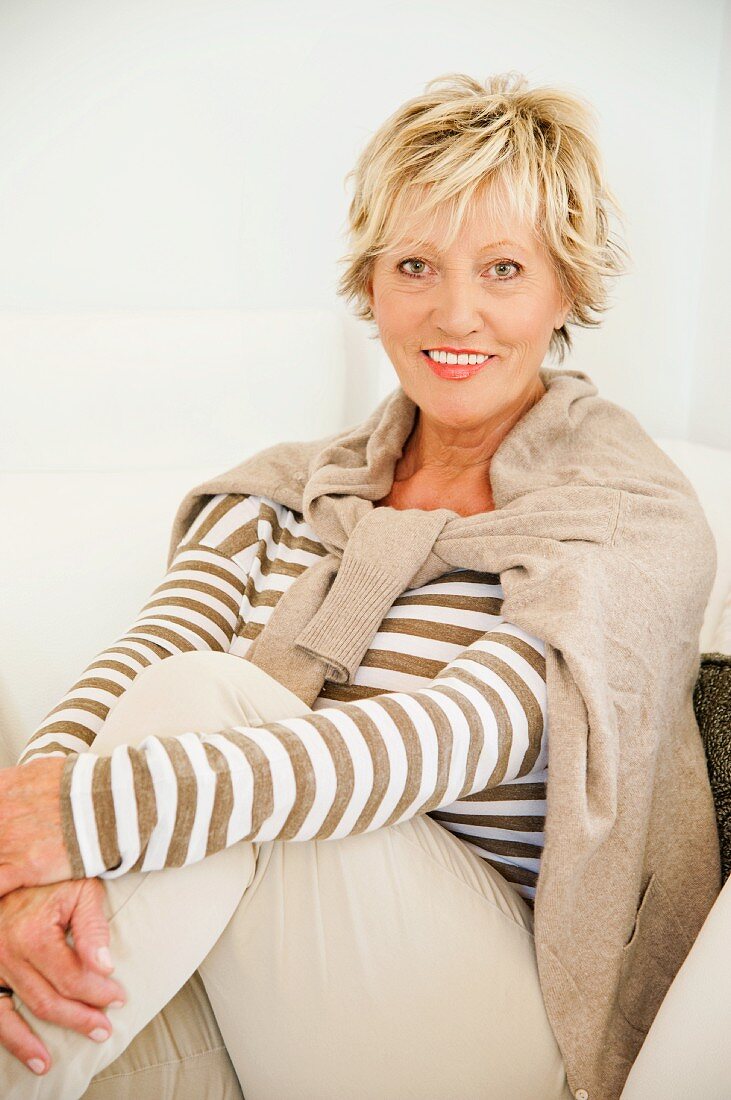 An older woman wearing light clothing sitting down