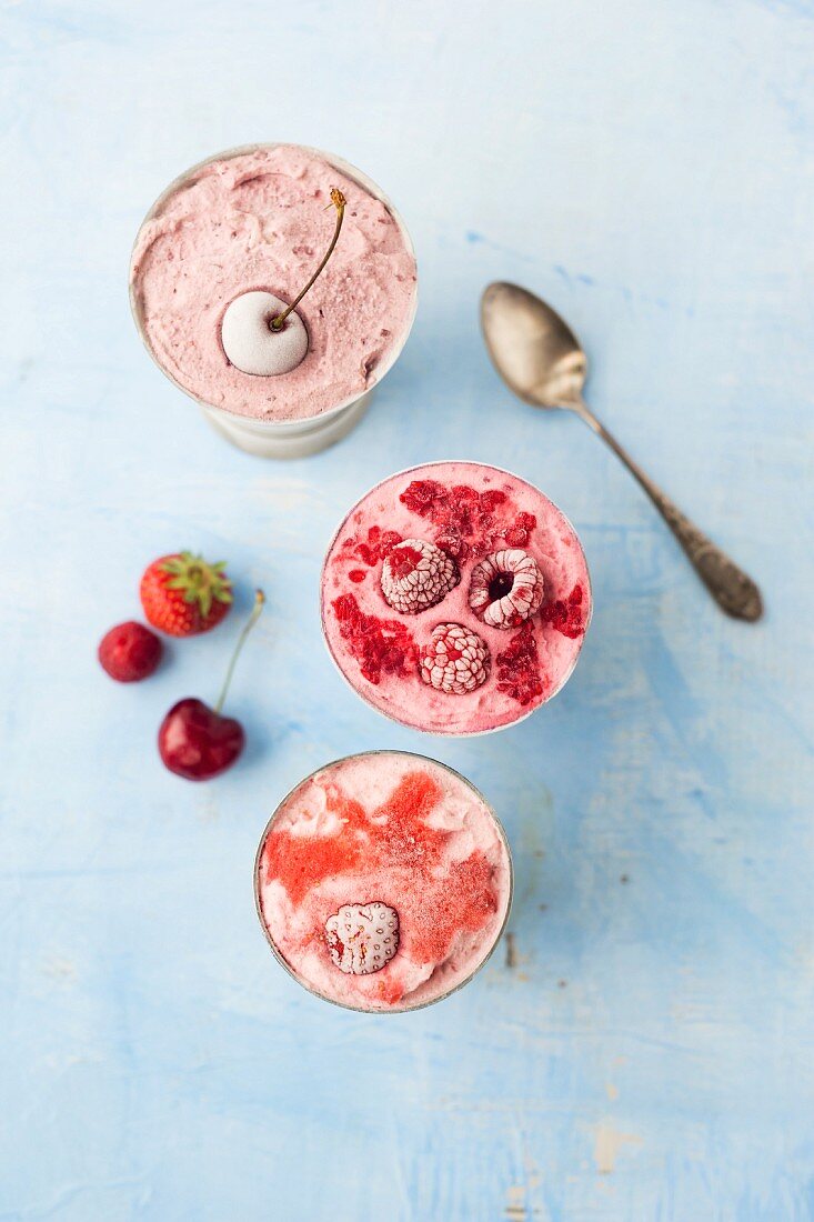 Strawberry ice, cherry ice cream and raspberry ice cream in metal cups (seen from above)
