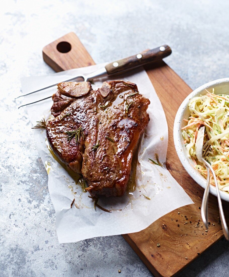 A T-bone steak with rosemary and coleslaw