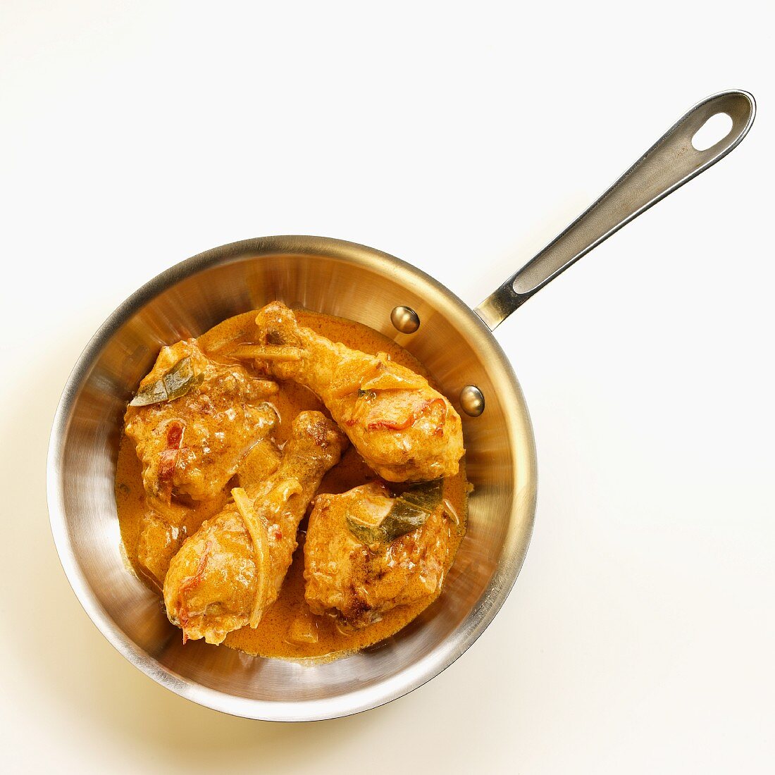 Hähnchenschenkel in roter Currysauce in Bratpfanne
