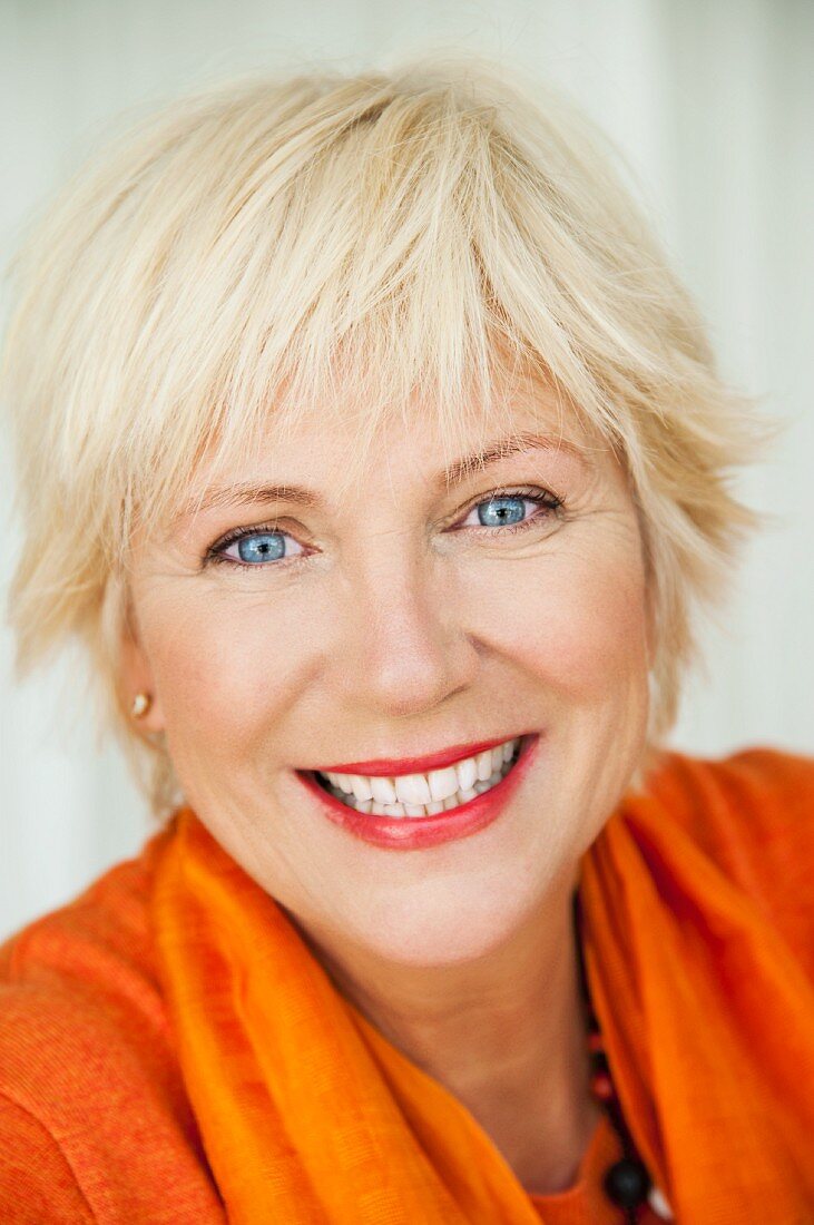 An older woman wearing an orange jumper and scarf