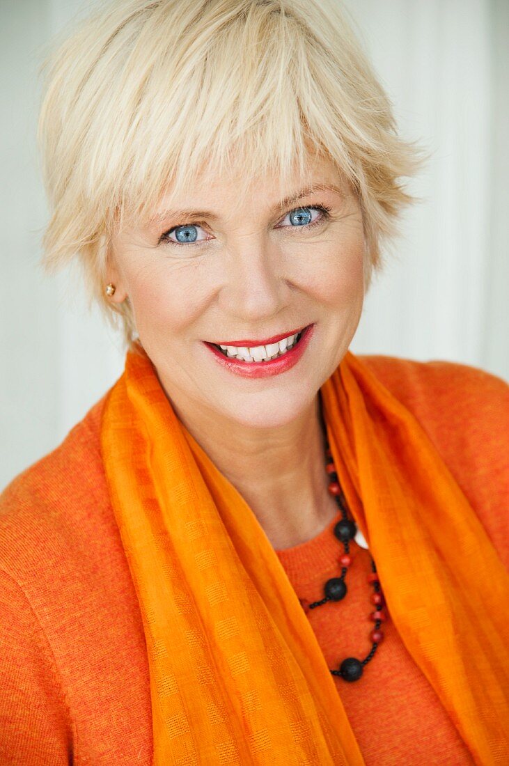 An older woman wearing an orange jumper and scarf