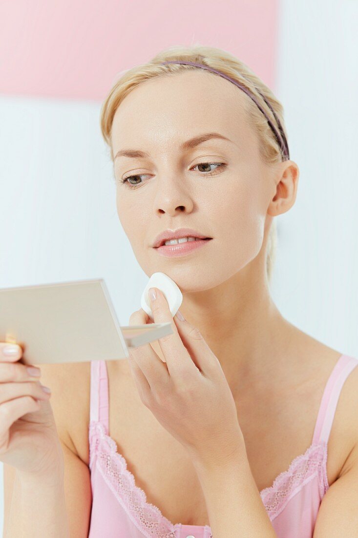 A young woman applying make-up with a sponge