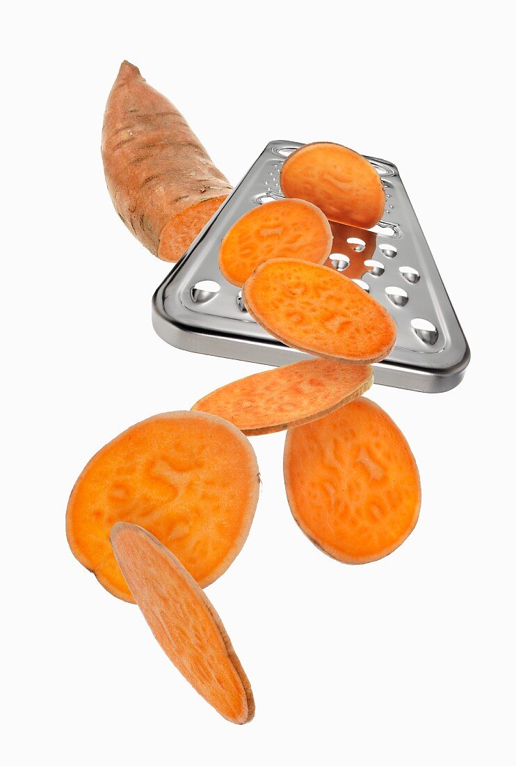 A grater with a sweet potato and sweet potato slices