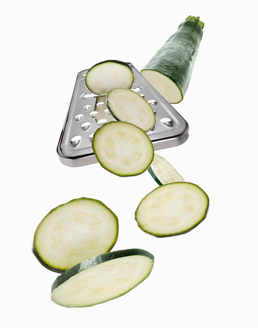 A grater with a courgette and courgette slices