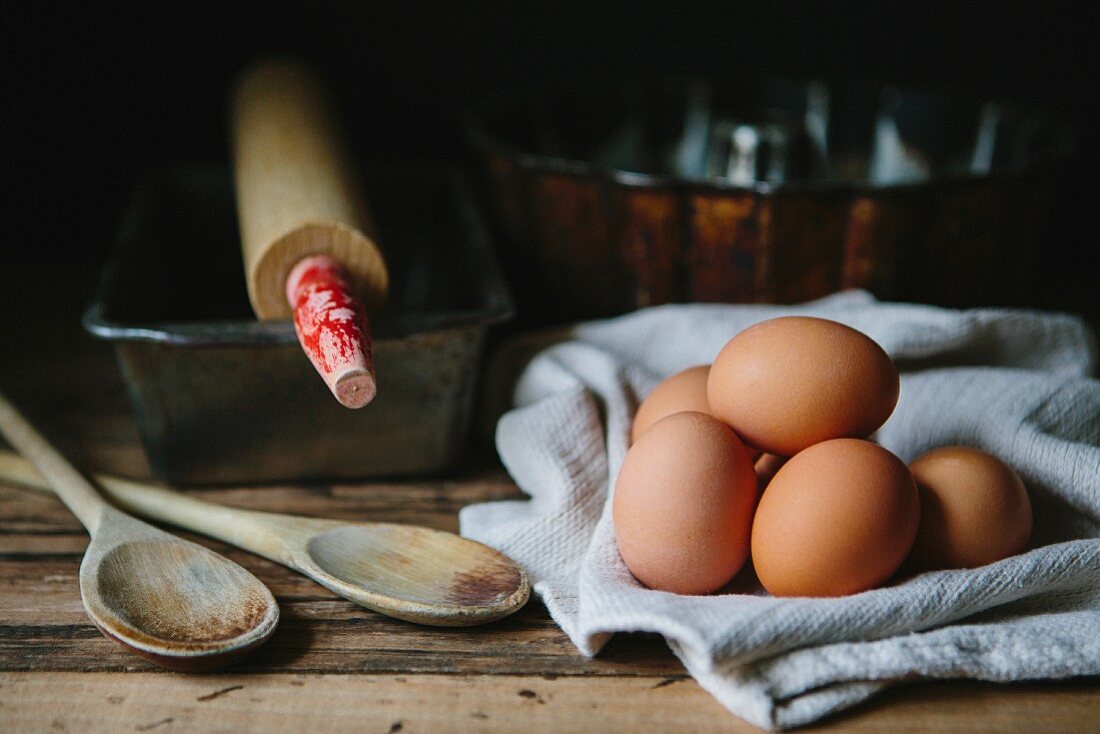 Brown eggs with wood spoons, baking tins and a rolling pin