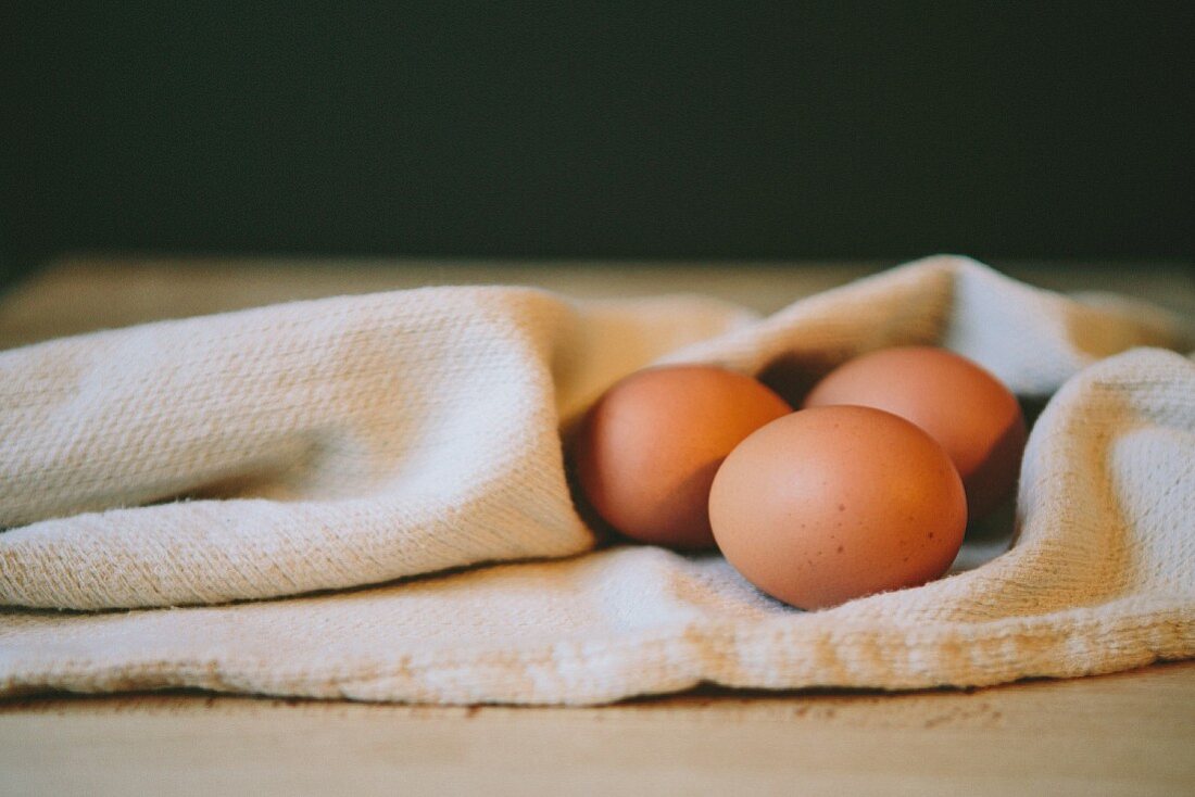 Drei braune Eier auf Geschirrtuch