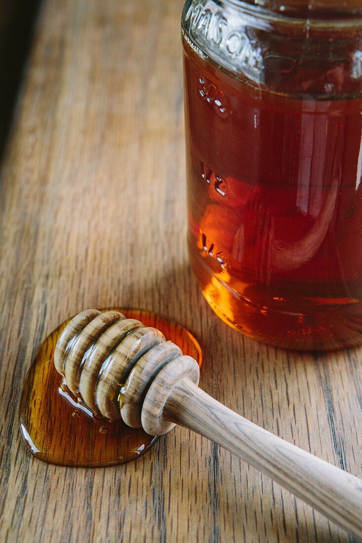 Honigglas und Honiglöffel auf Holztisch