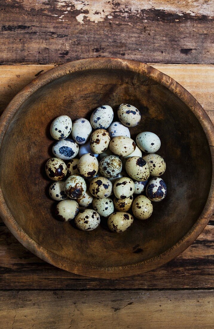 Speckled quail's eggs in a wooden bowl (seen from above)
